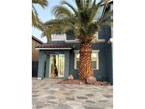 Two-story home with a stone patio, palm tree, and attached garage at 6336 Fence Post St, Las Vegas, NV 89148