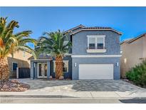 Two-story house with gray exterior, stone driveway, and palm trees at 6336 Fence Post St, Las Vegas, NV 89148