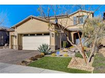 Two-story home with desert landscaping, stone accents, and a paver driveway leading to a two-car garage at 1610 Dire Wolf Avenue, North Las Vegas, NV 89084