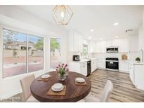 Bright kitchen with white cabinets, updated appliances, and a wood dining table at 3105 Birdwood Dr, Las Vegas, NV 89134