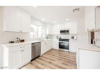 Modern white kitchen with stainless steel appliances and quartz countertops at 3105 Birdwood Dr, Las Vegas, NV 89134