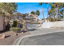 Two-story house with a tan exterior, two-car garage, and landscaped front yard at 8753 Arawana Pl, Henderson, NV 89074