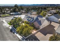 An inviting home with a brick driveway, mature trees, white picket fence, and a backdrop of scenic mountain views at 5110 N Valadez St, Las Vegas, NV 89149
