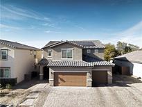 Two-story house with brown garage door and solar panels on the roof at 3439 Midnight Shadows Way, North Las Vegas, NV 89032