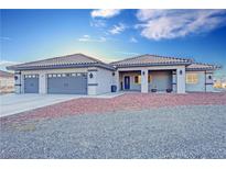Single-story home with attached two-car garage,desert landscaping, and a covered entryway at 2770 S Peggy St, Pahrump, NV 89048