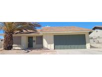 House exterior featuring a single-story home with a two-car garage and a palm tree at 2102 E Russell Rd, Las Vegas, NV 89119