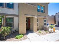 Tan two-story townhome with red door and landscaping at 9131 Hitmaker St, Las Vegas, NV 89113