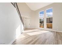 Bright living room with vaulted ceilings, large windows, and laminate flooring at 491 Kristin Ln, Henderson, NV 89011