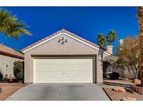 Single story home with a white garage door and desert landscaping at 9612 World Cup Dr, Las Vegas, NV 89117