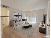 Spacious living room with wood-look floors, large windows and virtually staged furniture at 5710 Tropicana Ave # 1063, Las Vegas, NV 89122