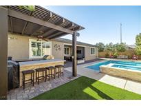 Outdoor kitchen, pool, spa, and pergola create a relaxing backyard oasis at 9820 Maiden Pink Ave, Las Vegas, NV 89149