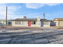 Ranch style home with red door, solar panels, and mature landscaping at 213 Valley Forge Ave, Henderson, NV 89015