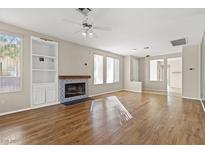 Bright living room featuring a fireplace, built-in shelving, wood floors, and large windows at 2292 Cassatt Dr, Henderson, NV 89074