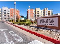 Manhattan Condominiums community sign sits on a manicured lawn with lush shrubs in front of the complex at 38 E Serene Ave # 134, Las Vegas, NV 89123