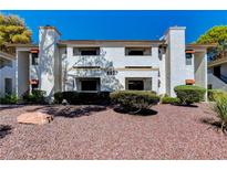 Inviting condo building exterior with landscaping and a rock garden at 6657 W Tropicana Ave # 201, Las Vegas, NV 89103