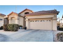 Tan house with brown roof, two-car garage, and landscaping at 22 Arborfield Ct, Henderson, NV 89012