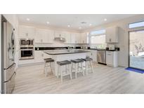 Bright kitchen features a large island with seating, stainless steel appliances and white cabinets at 8749 Black Cordon Rd, Las Vegas, NV 89139