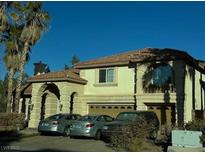 Two-story house with arched entryway and attached two-car garage, parked cars in driveway at 7616 Gossamer Wind St, Las Vegas, NV 89139