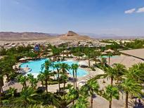 Expansive community pool featuring multiple areas, set amidst lush palm trees and a mountain backdrop at 334 Sea Rim Ave, Las Vegas, NV 89148