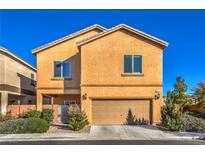 Two-story house with tan exterior, two-car garage, and landscaping at 9094 Palmas Altas St, Las Vegas, NV 89178