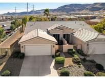 Single-story house with a two-car garage, desert landscaping, and mountain views at 10201 Premia Pl, Las Vegas, NV 89135