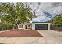 Updated single-story home with a red door, new landscaping, and a dark gray garage door at 145 Hancock St, Las Vegas, NV 89110