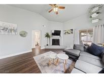 Cozy living room with a gray sofa, white brick fireplace, and wood-look flooring at 504 Crony Ave, Henderson, NV 89011