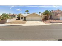 Beige house with two-car garage and desert landscaping at 707 Arrowhead Trl, Henderson, NV 89002