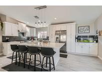 Bright kitchen with white cabinetry, stainless steel appliances, large island with seating, and stylish backsplash at 7277 Abbeyville Dr, Las Vegas, NV 89119