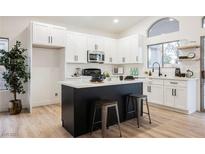 Bright kitchen with white cabinetry, island with bar stool seating, and modern stainless steel appliances at 6304 Tanzanite Ave, Las Vegas, NV 89130