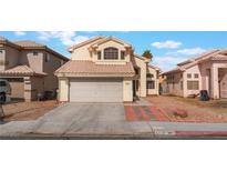 Two-story home with tan exterior, tile roof, two-car garage and desert landscaping at 6712 Painted Canyon Ct, Las Vegas, NV 89130