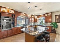 An oversized kitchen island with granite counters sits beneath decorative lighting at 6595 Creekside Cellars Ct, Las Vegas, NV 89139