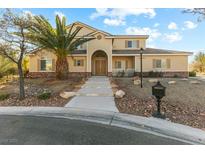 Two-story house with tan siding, landscaping, and a palm tree in the front yard at 7611 Leybourne Ct, Las Vegas, NV 89131