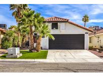 Single story home with red door, palm trees, and a black garage door at 2674 Alwoodley Cir, Las Vegas, NV 89142