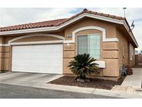 Tan stucco house with white garage door, landscaping, and a reddish-brown tile roof at 9073 Purple Leaf St, Las Vegas, NV 89123