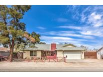 Charming single-story home with a red fence, mature trees, and a two car garage at 4720 E Wyoming Ave, Las Vegas, NV 89104