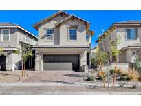 Two-story house with gray siding, dark garage door, and landscaped front yard at 710 Bamboo Bend Pl, Henderson, NV 89011