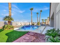 Inviting backyard pool featuring a waterfall, mature palms, and a spacious patio area at 278 Iron Duke Ave, Las Vegas, NV 89183