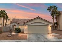 Beige house with a two-car garage and landscaped yard at 3119 Crownline Ct, North Las Vegas, NV 89031