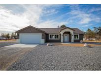 Charming single-story home features a gravel front yard, two-car garage, and covered entrance at 3880 Leonard St, Pahrump, NV 89060