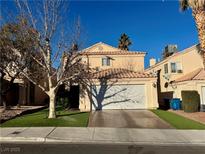 Tan two-story house with a white garage door and artificial turf at 433 Jubilation Dr, Las Vegas, NV 89145