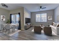 Spacious living room, virtually staged, with hardwood floors and access to a balcony at 6955 N Durango Dr # 1048, Las Vegas, NV 89149