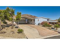 Charming single-story home boasts a spacious driveway, covered parking, and drought-tolerant landscaping against a scenic mountain backdrop at 648 Mount Blackburn Ln, Boulder City, NV 89005