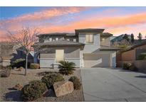 Two-story house with beige exterior, landscaped yard, and a two-car garage at 12 Oro Valley Dr, Henderson, NV 89052