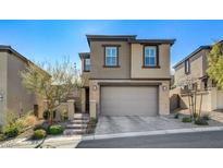 Two-story home with tan and brown exterior, gray garage door and stone accents at 889 Ariel Heights Ave, Las Vegas, NV 89138