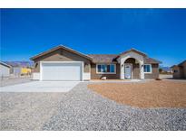 Inviting single-story home features a neutral color palette and a well-manicured gravel yard at 5841 Genoa Ave, Pahrump, NV 89060