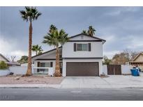 Two-story house with brown garage door and palm trees at 881 Stonehenge St, Las Vegas, NV 89110