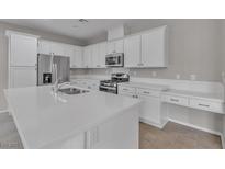 A modern kitchen featuring white cabinetry, stainless steel appliances and solid surface countertops at 5233 Fiery Sky Ridge St, Las Vegas, NV 89148