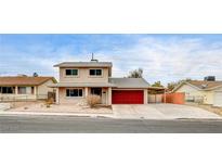 Beige two-story house with red garage door and landscaped yard at 7232 Raincloud Dr, Las Vegas, NV 89145