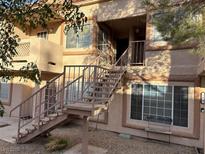 A two-story apartment complex with private entrance stairways, neutral paint, and a small bench at 1600 N Torrey Pines Dr # 202, Las Vegas, NV 89108